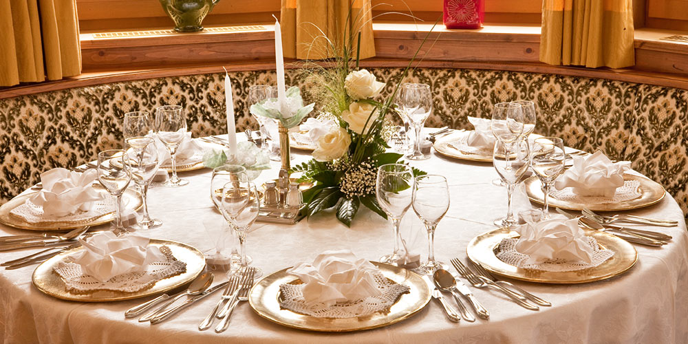 Gedeckter Tisch mit Kerzen und zu Blumen gefaltete Servietten - Hotel Hubertushof